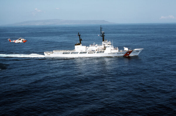 Photo: Aerial starboard beam view of the Coast Guard high endurance cutter Midgett (WHEC-726) underway. A Coast Guard HH-3F Pelican helicopter is in flight behind the ship.