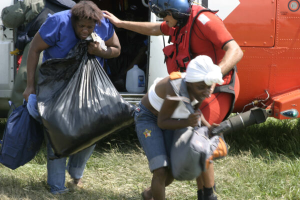 Photo: A U.S. Coast Guard aircrew member helps a rescued Hurricane Katrina survivor exiting the helicopter.