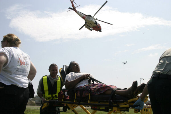 Photo: A U.S. Coast Guard MH-60 Jayhawk Helicopter flies over a Hurricane Katrina victim being given medical attention.