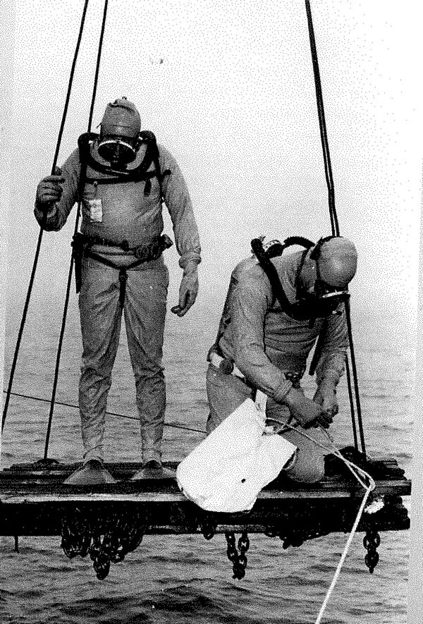 Black and white photo of divers preparing to enter water.