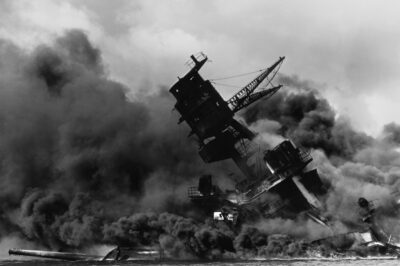 Photo: The wreck of the battleship USS Arizona in flames and sitting on the harbor bottom.