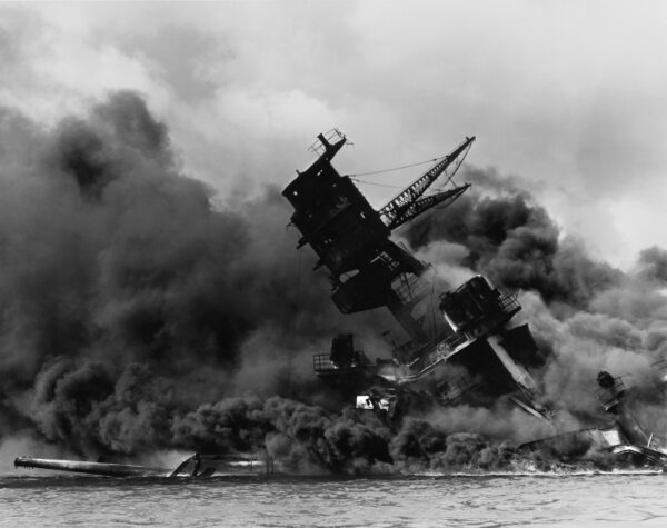 Photo: The wreck of the battleship USS Arizona in flames and sitting on the harbor bottom.