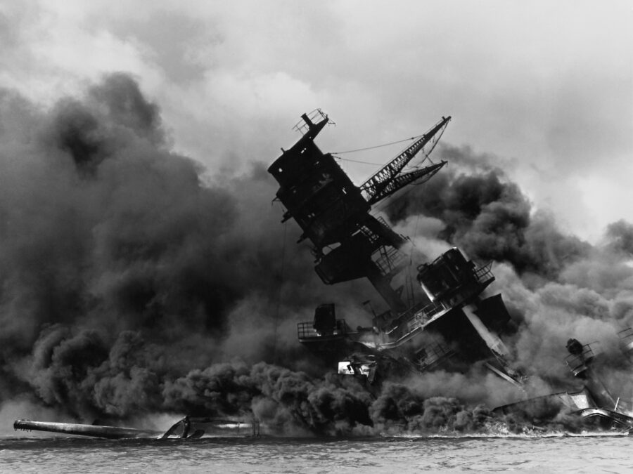 Photo: The wreck of the battleship USS Arizona in flames and sitting on the harbor bottom.