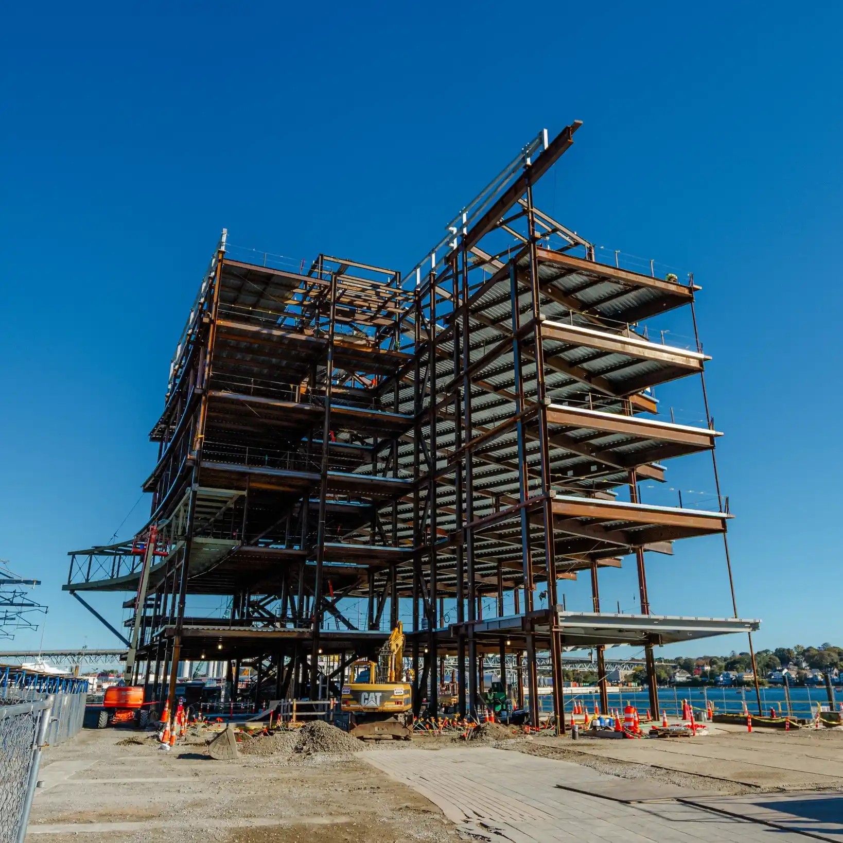 Photo: A construction site with the frame of a building next to the water.