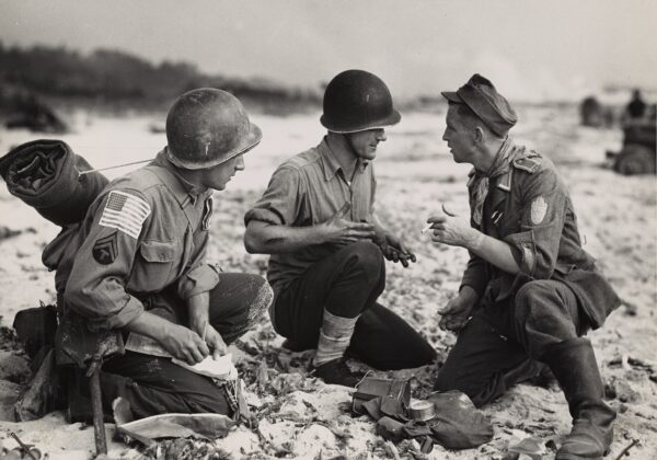Photo: Three uniformed servicemen on the beach.